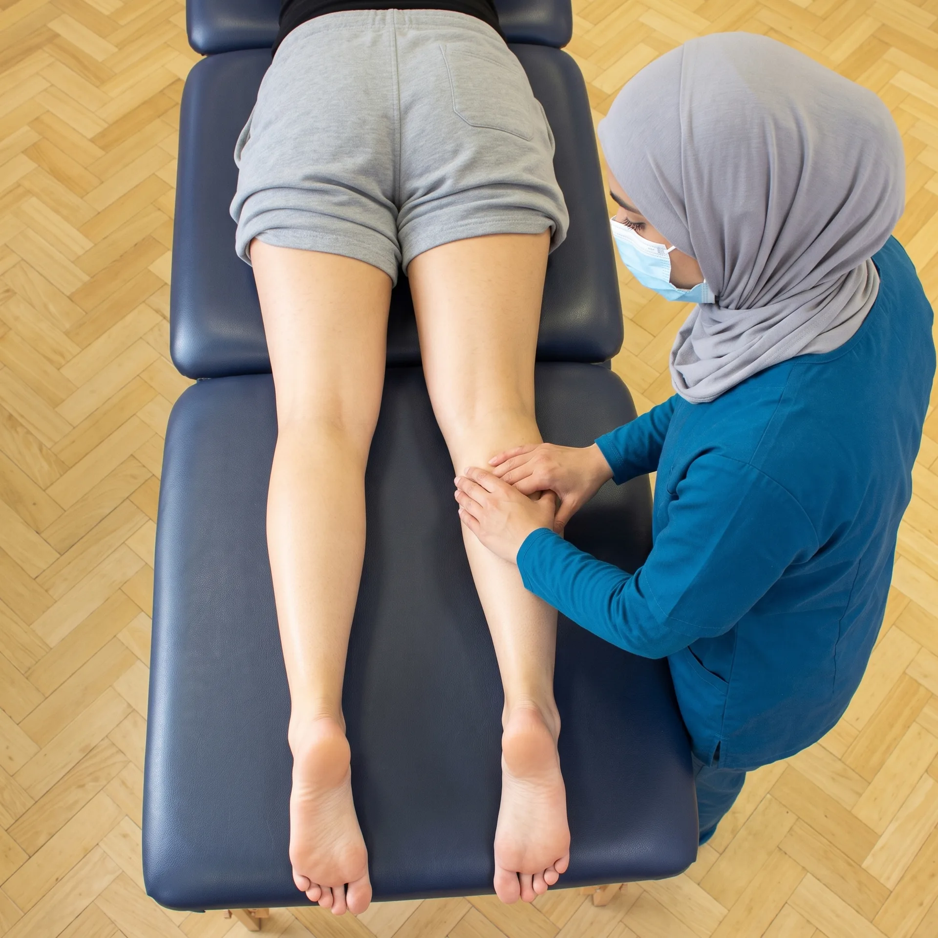 Physiotherapist assessing a patient's leg for overuse-related pain
