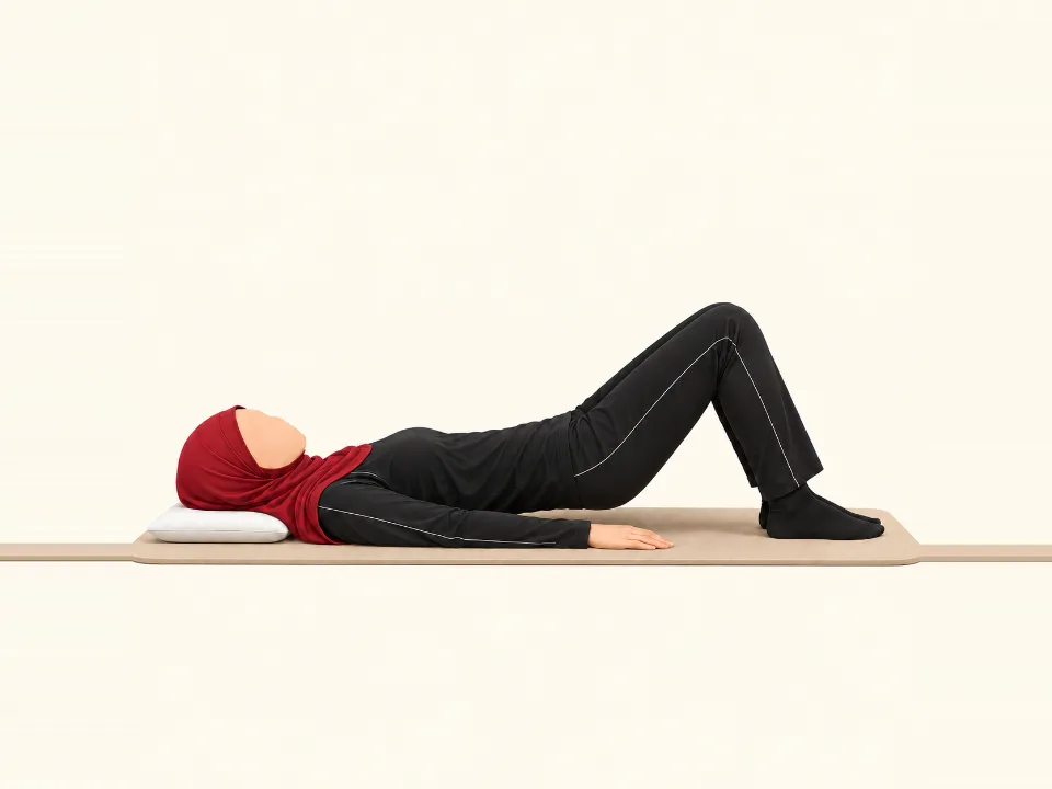 Woman in a red hijab lying on her back with knees bent, lifting her hips into a bridge.